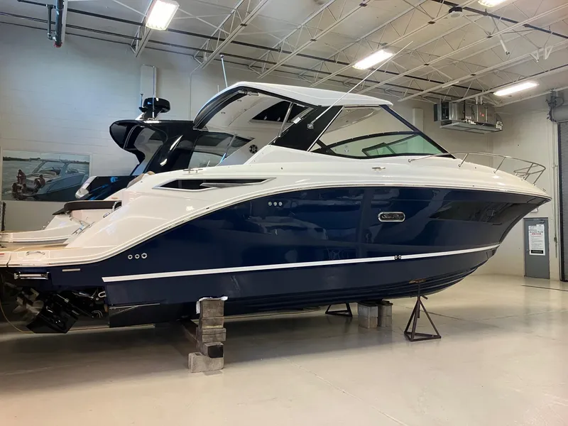 Slide: The Image of 2025 Sea Ray Sundancer 320 yacht in showroom, sleek design, blue and white exterior. - 4