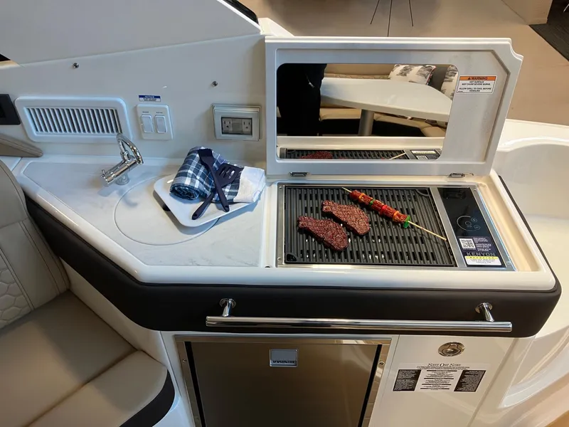 Slide: The Image of Outdoor grill on 2025 Sea Ray Sundancer 320 yacht with food and utensils. - 8