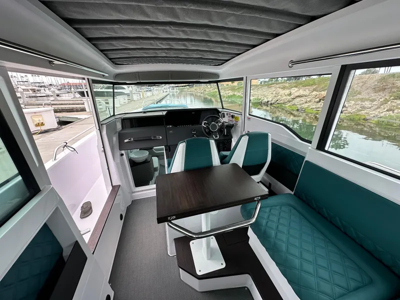 Slide: The Image of Interior of 2023 Axopar 37 XC Crosscabin with seating and table, dockside view. - 4