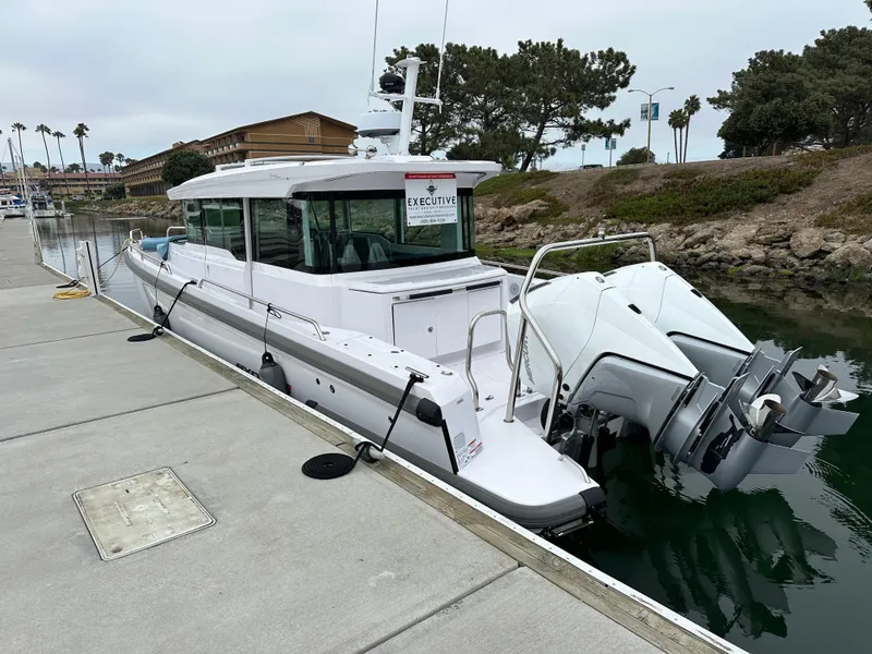 Slide: The Image of 2023 Axopar 37 XC Crosscabin docked by the water, showcasing sleek design and powerful engines. - 8