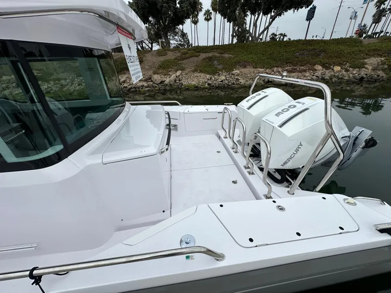 Slide: The Image of 2023 Axopar 37 XC Crosscabin with dual Mercury outboard engines, docked by a scenic shoreline. - 9