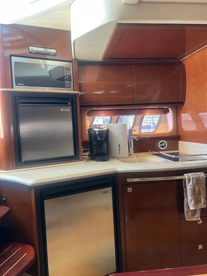 Slide: The Image of 2008 Sea Ray 38 Sundancer yacht kitchen with microwave, fridge, and wooden cabinetry. - 32
