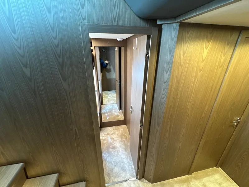 Slide: The Image of Interior hallway of 2022 Ferretti Yachts 550, featuring wood paneling and carpeted flooring. - 14