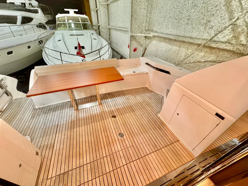 Slide: The Image of 2022 Ferretti Yachts 550 deck with wooden table, docked in a marina. - 78