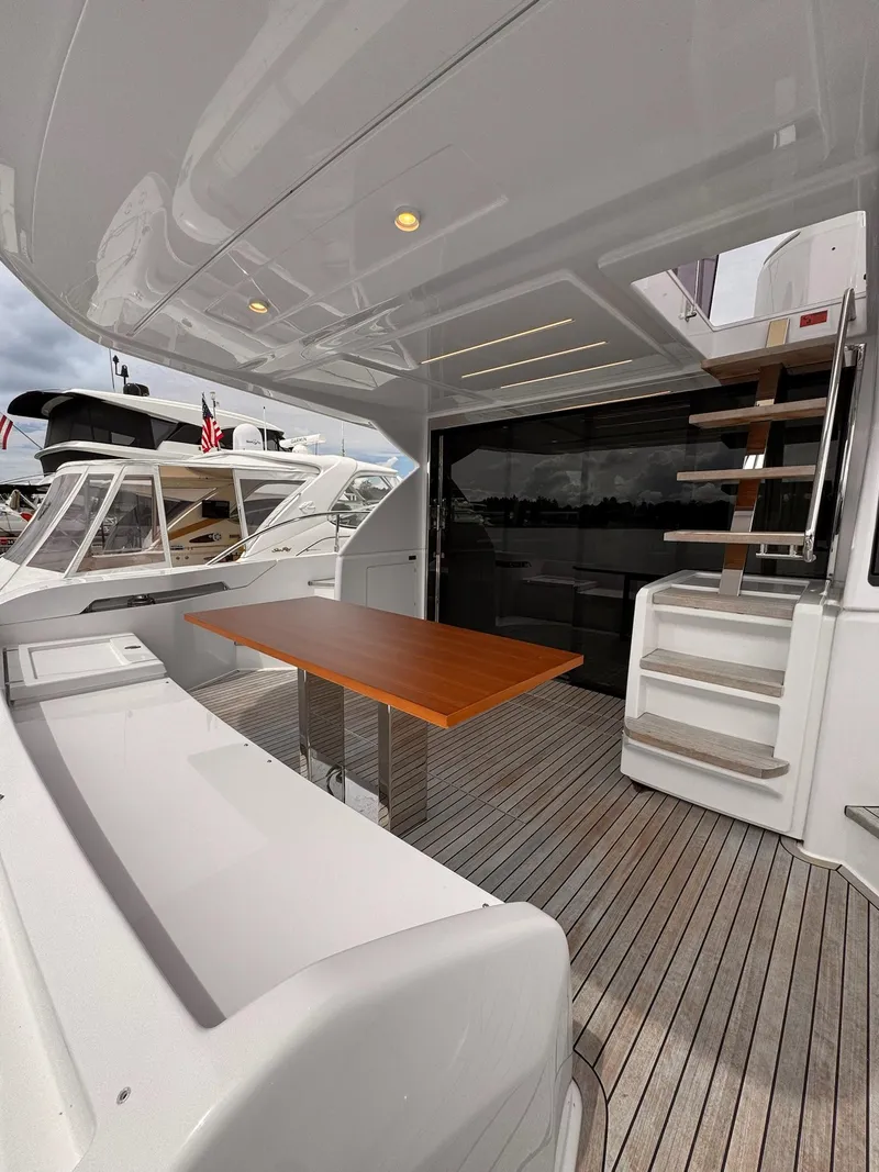 Slide: The Image of 2022 Ferretti Yachts 550 deck with wooden table and modern staircase. - 1