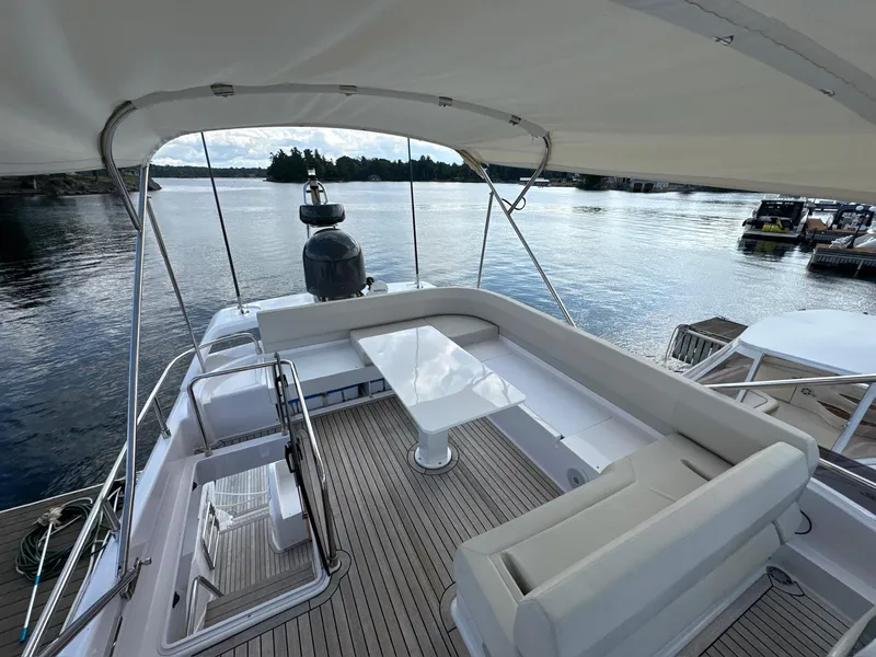 Slide: The Image of Luxurious 2022 Ferretti Yachts 550 deck with seating and table, overlooking serene waters. - 26