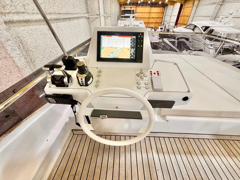Slide: The Image of 2022 Ferretti Yachts 550 helm with navigation display and controls in a marina setting. - 69