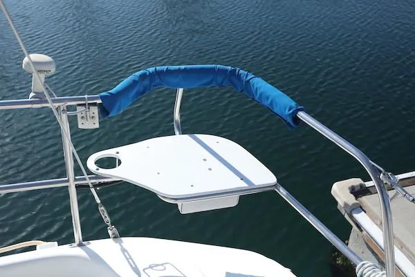 Slide: The Image of Sailboat stern rail with blue padding on a 2000 Catalina 320, docked by calm water. - 16