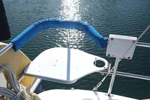 Slide: The Image of Catalina 320 sailboat stern with blue railing, reflecting sunlight on water. - 17