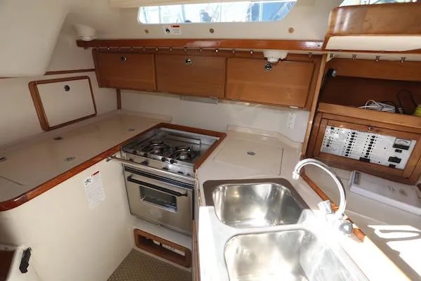 Slide: The Image of Interior of 2000 Catalina 320 sailboat kitchen with stove, sink, and wooden cabinetry. - 5