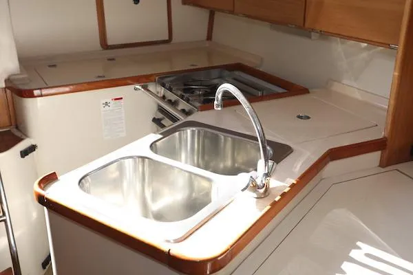 Slide: The Image of 2000 Catalina 320 yacht kitchen with dual sinks and stove, featuring wood accents. - 8