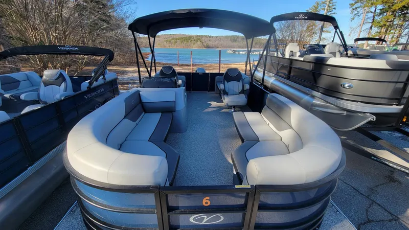 Slide: The Image of 2023 Veranda Vista 20 RC pontoon boat with spacious seating, docked by a scenic lake. - 6