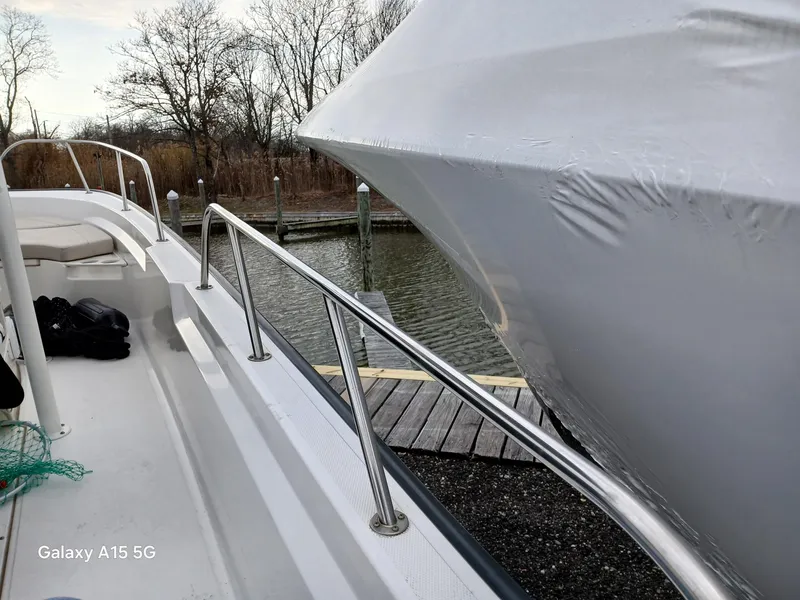 Slide: The Image of 2018 Boston Whaler 190 Montauk docked, with protective cover, near a calm waterfront. - 21