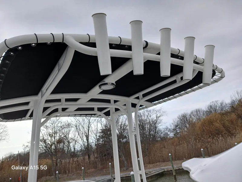Slide: The Image of 2018 Boston Whaler 190 Montauk T-top with rod holders, docked near trees. - 16