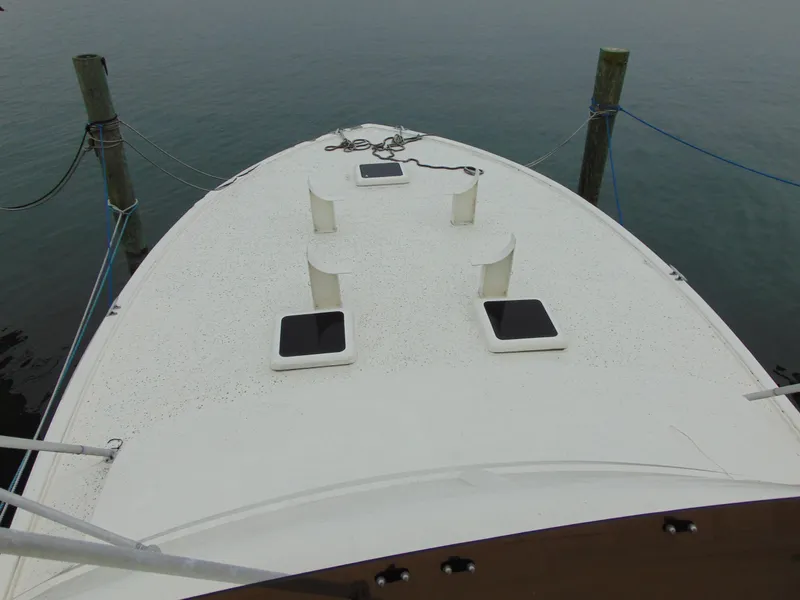 Slide: The Image of 1981 Post 46 Sportfish boat deck with hatches and cleats, docked on calm water. - 14