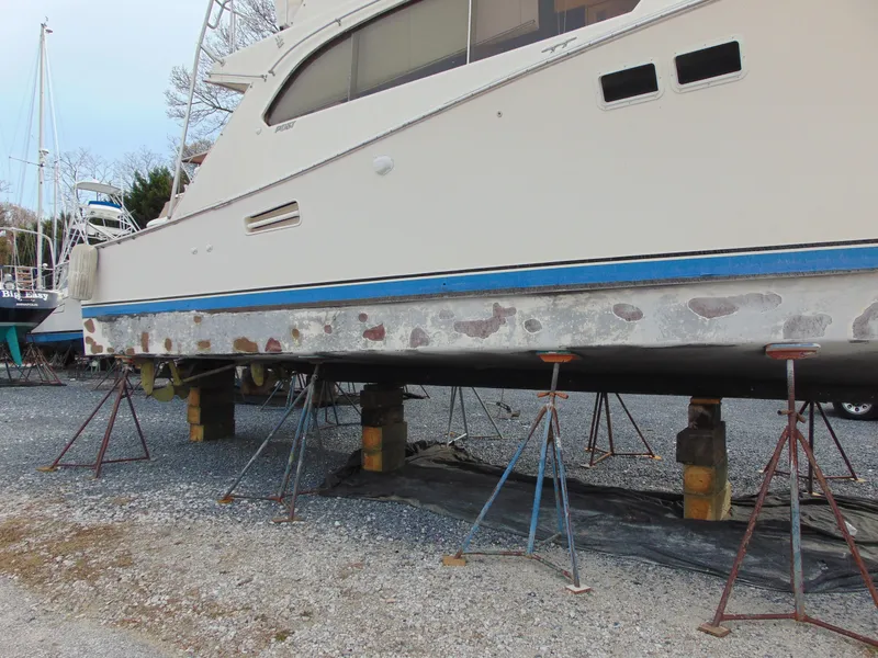 Slide: The Image of 1981 Post 46 Sportfish boat on stands, undergoing maintenance on gravel surface. - 26