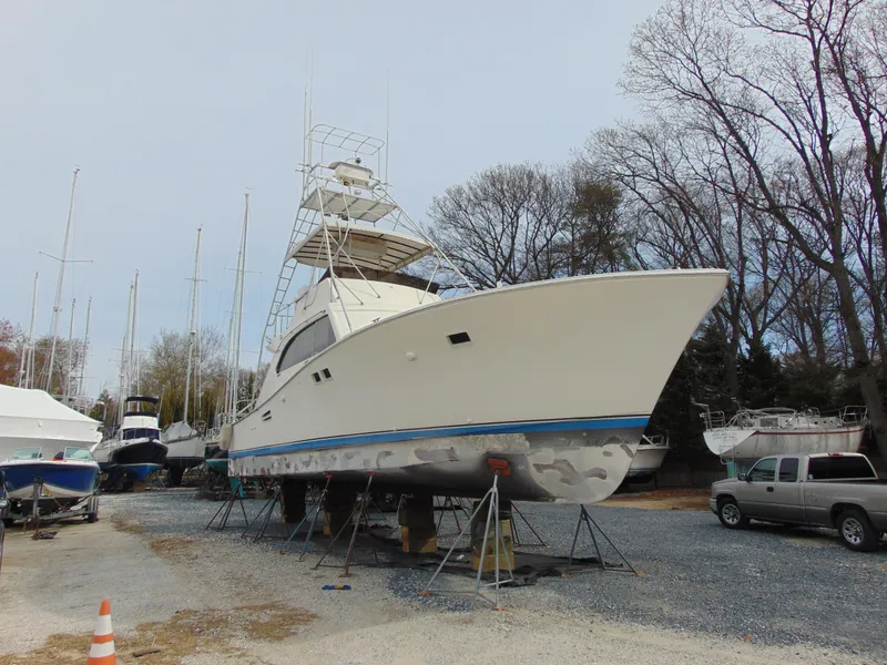 Slide: The Image of 1981 Post 46 Sportfish boat on stands in a boatyard, surrounded by trees and other vessels. - 27