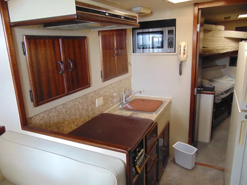 Slide: The Image of 1981 Post 46 Sportfish yacht interior with kitchenette, microwave, and wooden cabinets. - 48