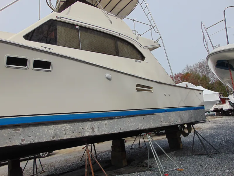 Slide: The Image of 1981 Post 46 Sportfish boat on stands, side view, beige hull with blue stripe. - 30