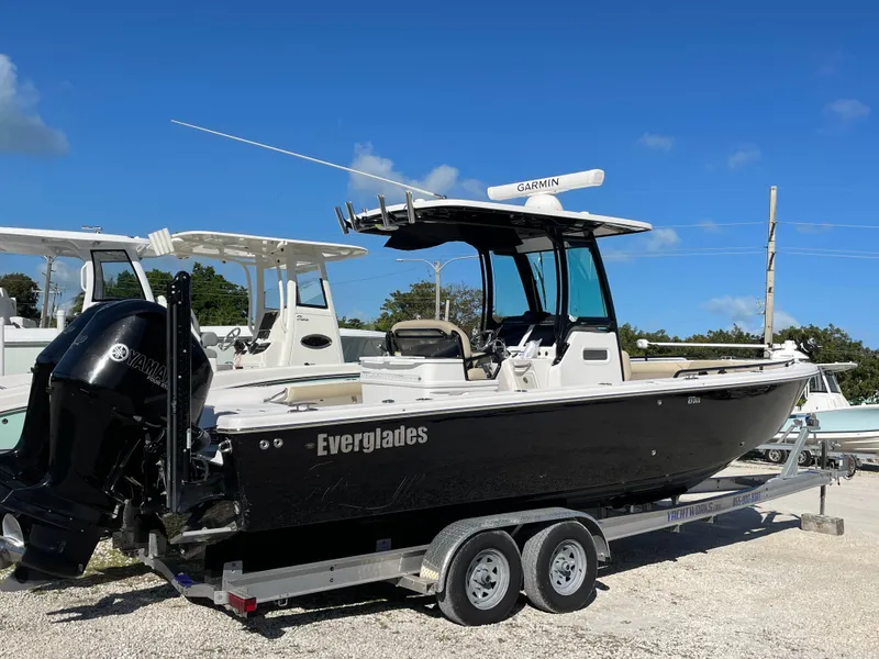 The Image of 2020 Everglades 273 Center Console boat on trailer, black hull, clear sky background. - 0