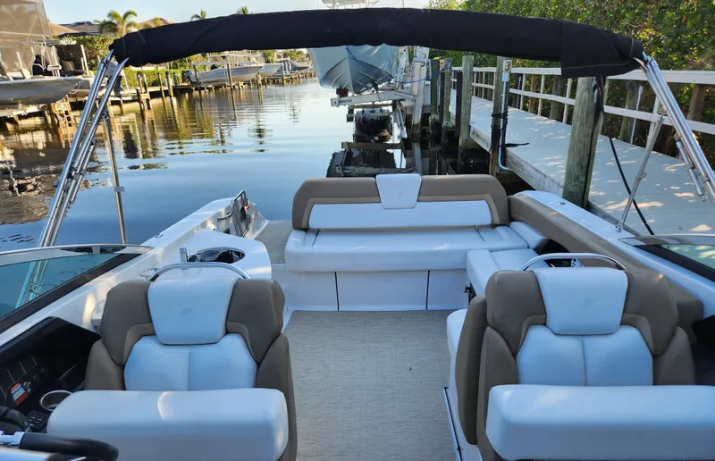 Slide: The Image of 2015 Four Winns Horizon H290 boat interior with plush seating and canopy, docked by a serene waterfront. - 8