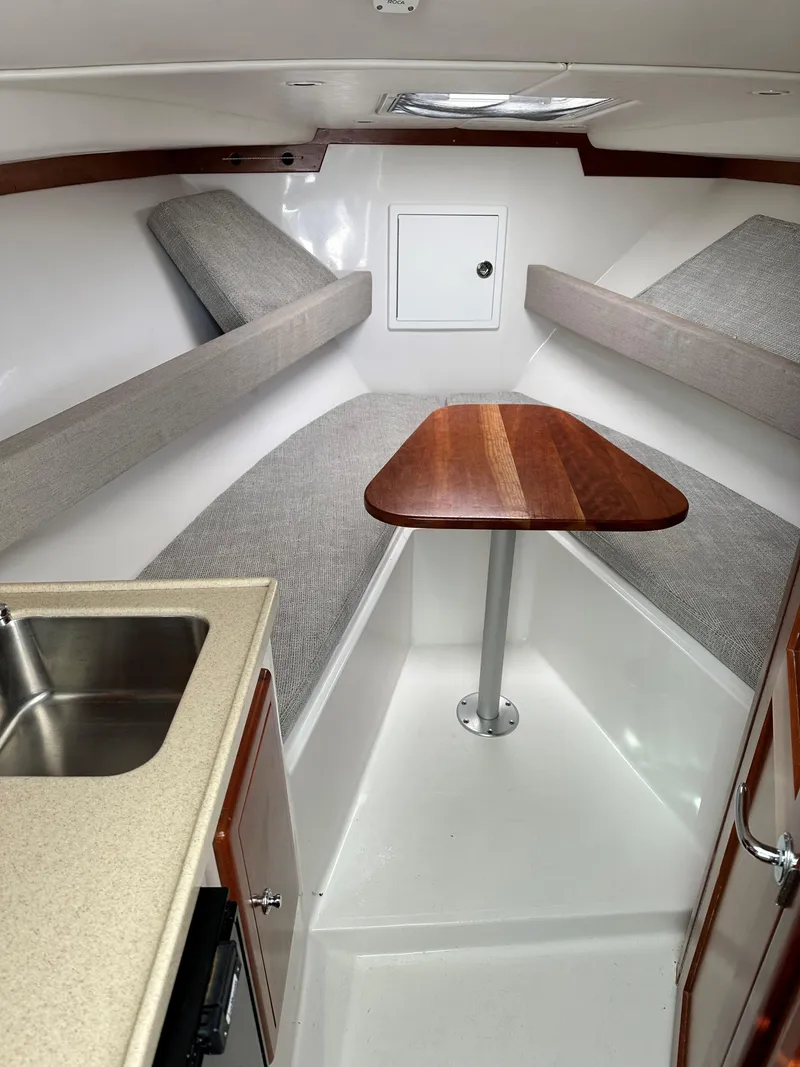 Slide: The Image of 2017 Albemarle 27 Express cabin interior with table, seating, and kitchenette. - 22