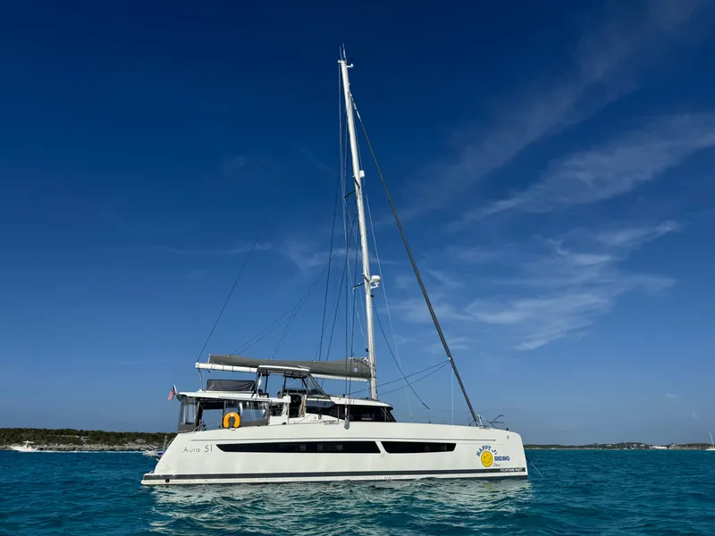 Slide: The Image of 2024 Fountaine Pajot Aura 51 catamaran sailing on clear blue waters under a sunny sky. - 0
