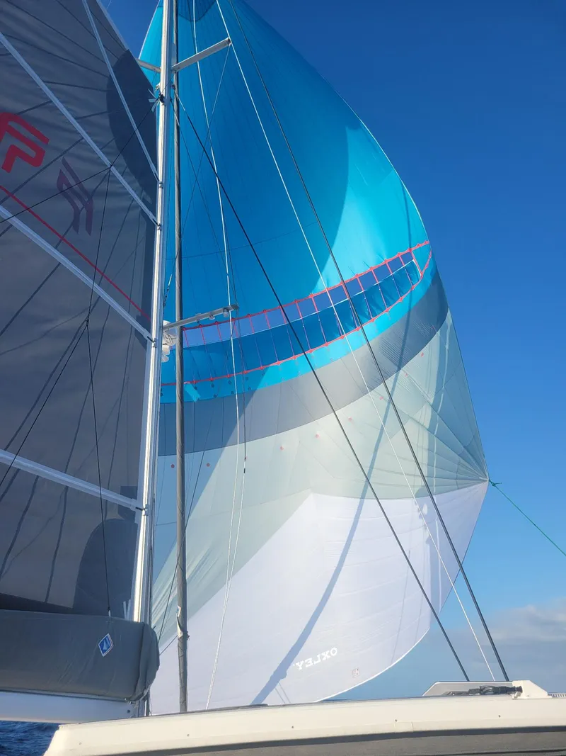 Slide: The Image of 2024 Fountaine Pajot Aura 51 sailboat with vibrant blue and white sails against a clear sky. - 4