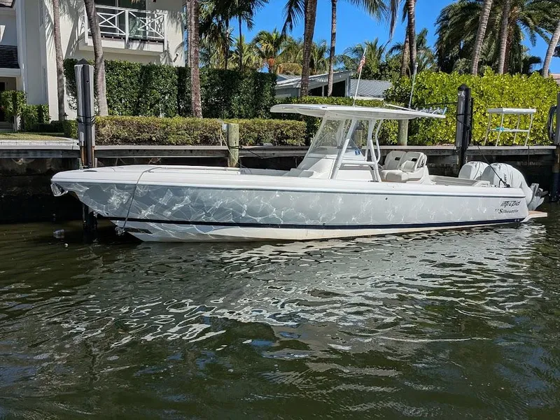 Slide: The Image of Intrepid 327 Center Console 2017 boat with upgraded 2019 motors docked by palm trees. - 2