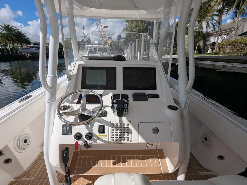 Slide: The Image of Intrepid 327 Center Console 2017 boat dashboard with upgraded motors, docked by palm trees. - 29