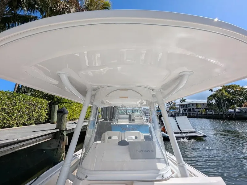 Slide: The Image of Intrepid 327 Center Console boat docked, showcasing helm and T-top under clear blue sky. - 41