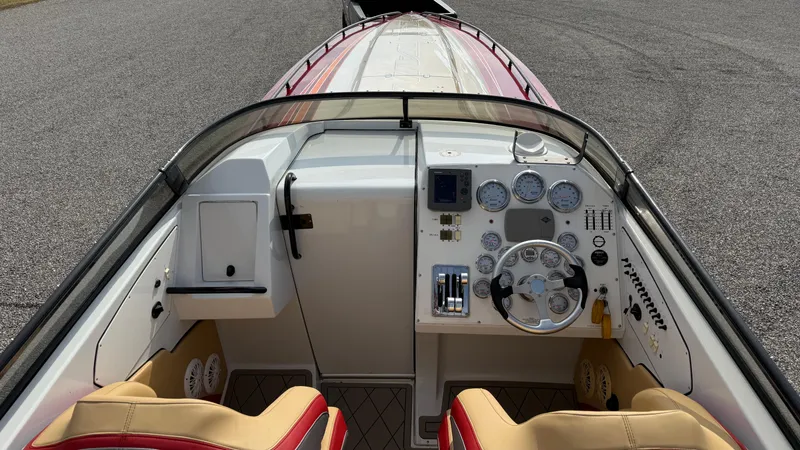Slide: The Image of 2007 Fountain 42 Lightning boat cockpit with gauges and steering wheel, featuring red and beige seats. - 17
