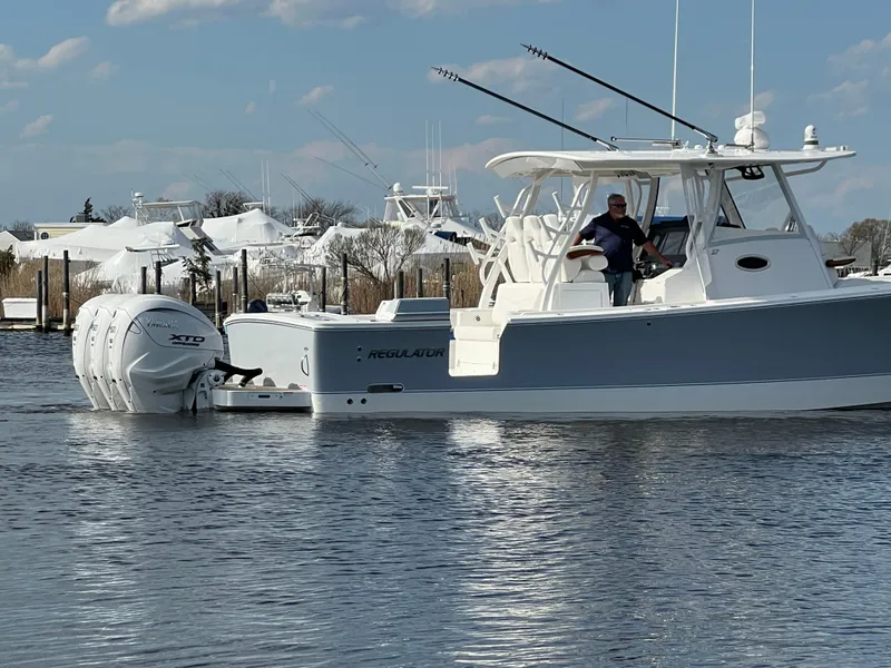 Slide: The Image of 2024 Regulator 37 boat on water with dual engines, clear sky, and marina background. - 15