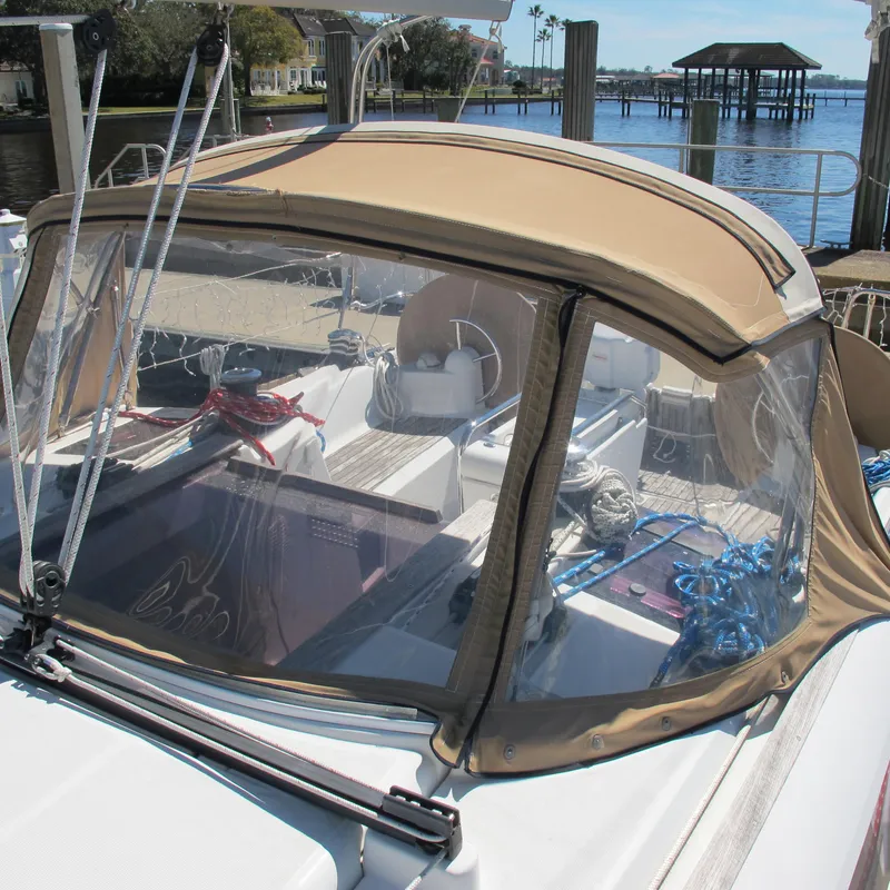 Slide: The Image of 2013 Jeanneau Sun Odyssey 379 sailboat cockpit with tan canopy, docked by the water. - 11