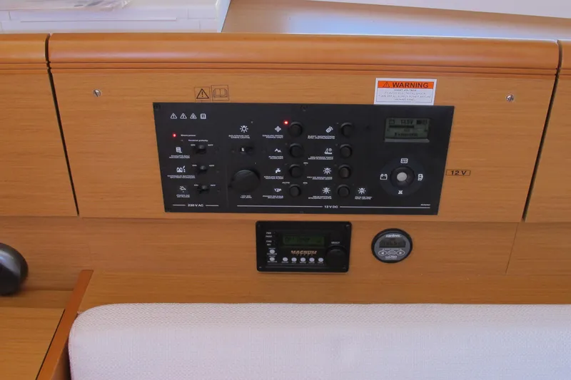 Slide: The Image of Control panel of a 2013 Jeanneau Sun Odyssey 379 sailboat, featuring various switches and displays. - 67