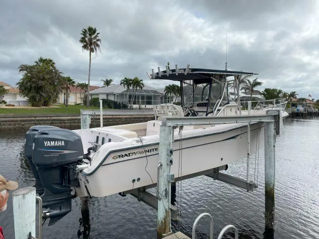 Slide: The Image of 2005 Grady-White 283 RELEASE boat with Yamaha engine on lift, docked by waterfront homes. - 1