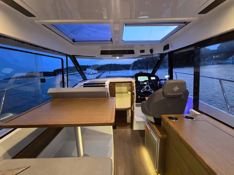 Slide: The Image of Interior of 2021 Jeanneau NC895 boat with modern seating and navigation area at dusk. - 10