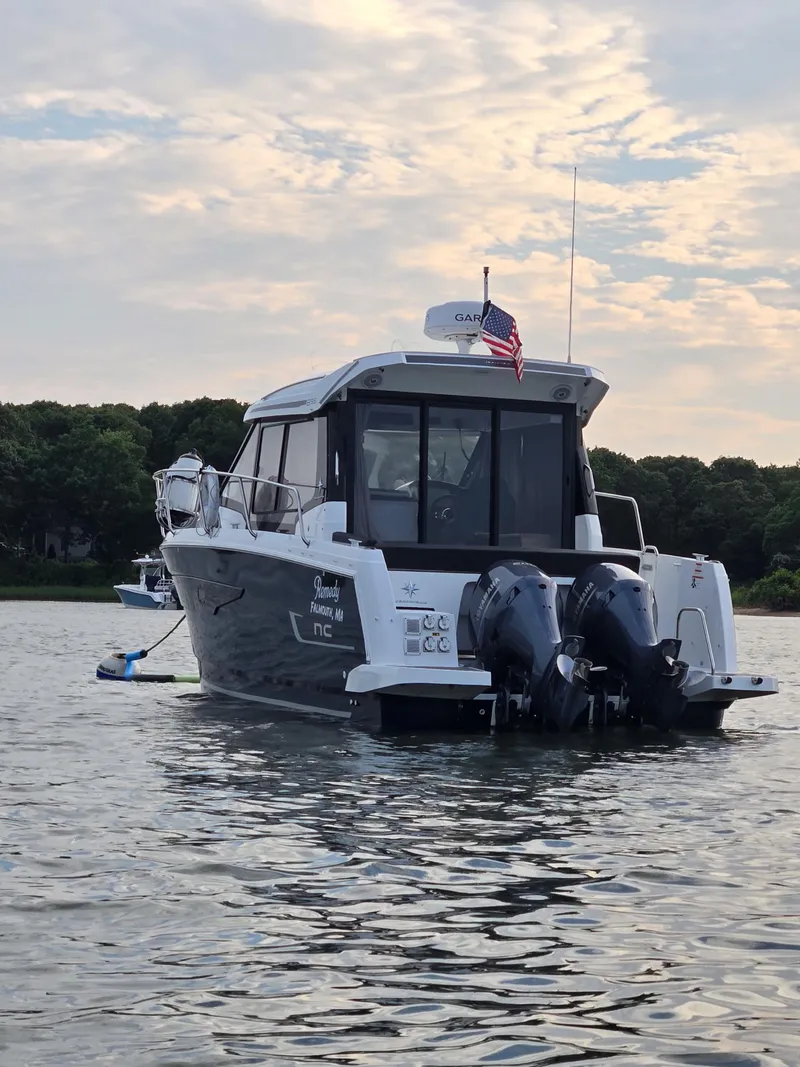 Slide: The Image of 2021 Jeanneau NC895 boat on calm water with twin outboard motors. - 2