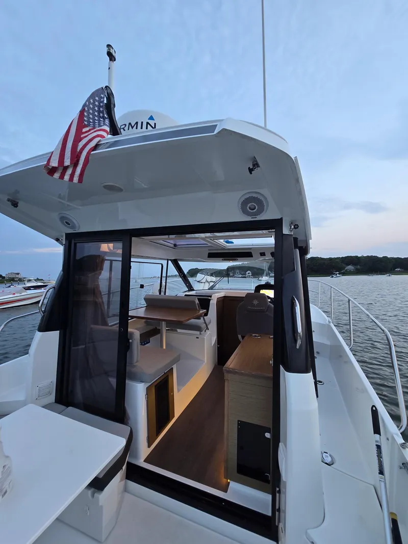 Slide: The Image of 2021 Jeanneau NC895 boat interior with American flag, docked at sunset. - 27