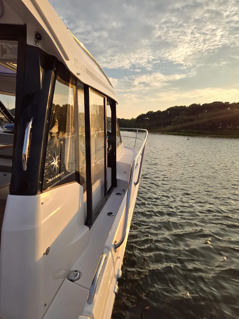 Slide: The Image of 2021 Jeanneau NC895 boat cruising on a serene river at sunset. - 31