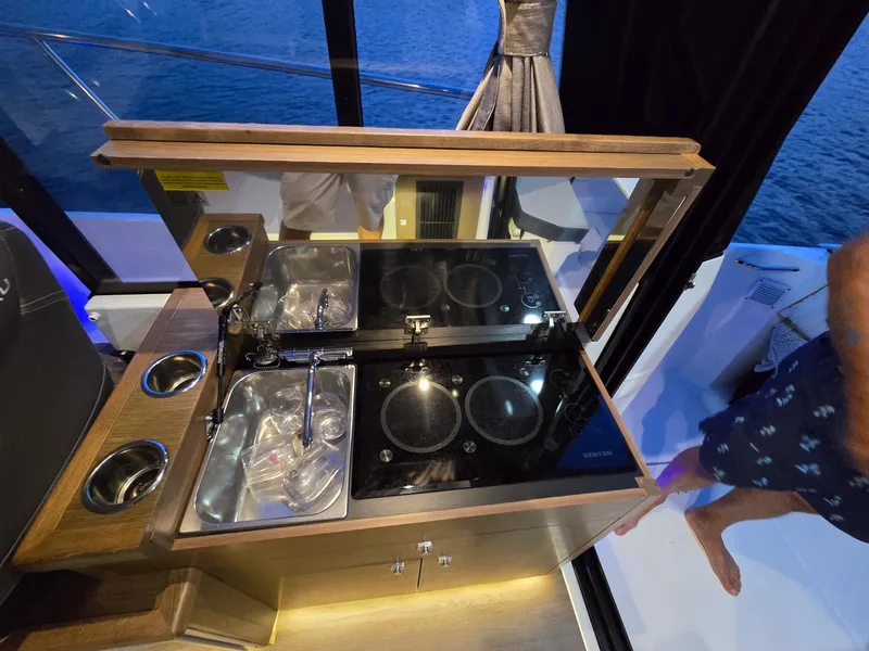 Slide: The Image of Compact kitchen area on a 2021 Jeanneau NC895 boat, featuring a stove and sink. - 7