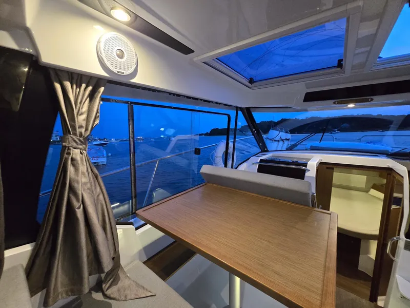 Slide: The Image of Interior of 2021 Jeanneau NC895 boat with table, windows, and evening view. - 9