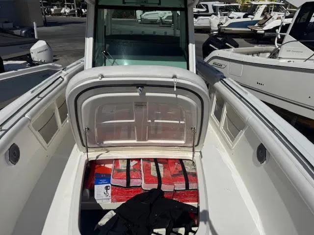 Slide: The Image of 2016 Boston Whaler 350 Outrage boat with open storage compartment, docked among other boats. - 8