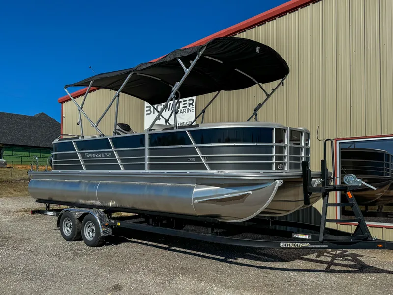 The Image of 2024 Berkshire 24RFXLE pontoon boat on trailer, parked outside a building. - 0
