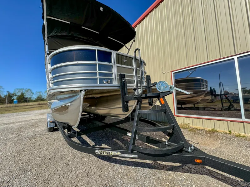 Slide: The Image of 2024 Berkshire 24RFXLE pontoon boat on trailer, parked near a building. - 1