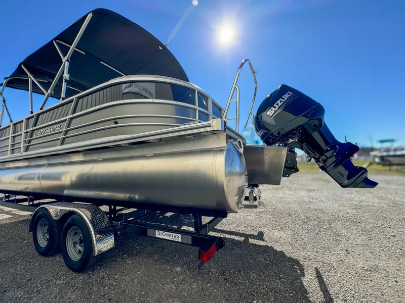 Slide: The Image of 2024 Berkshire 24RFXLE pontoon boat with Suzuki outboard motor on trailer under sunny sky. - 4