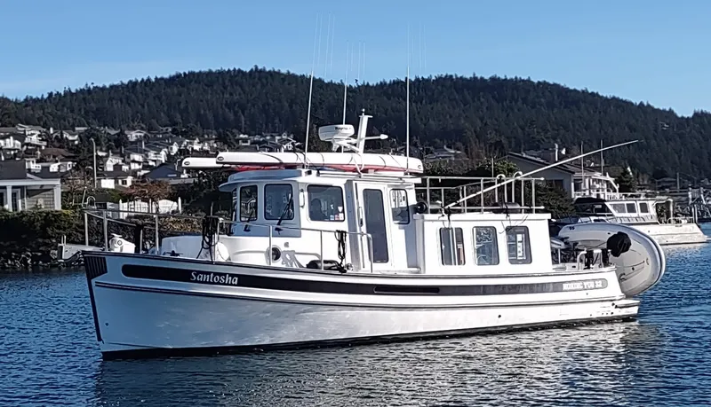 Slide: The Image of 2006 Nordic Tug 32 boat on water with scenic background. - 0