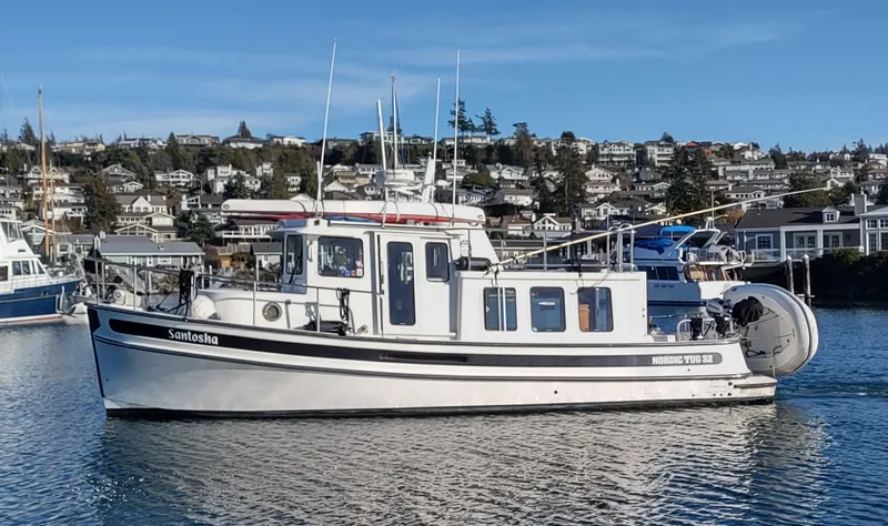Slide: The Image of 2006 Nordic Tug 32 boat on calm water with scenic coastal background. - 1