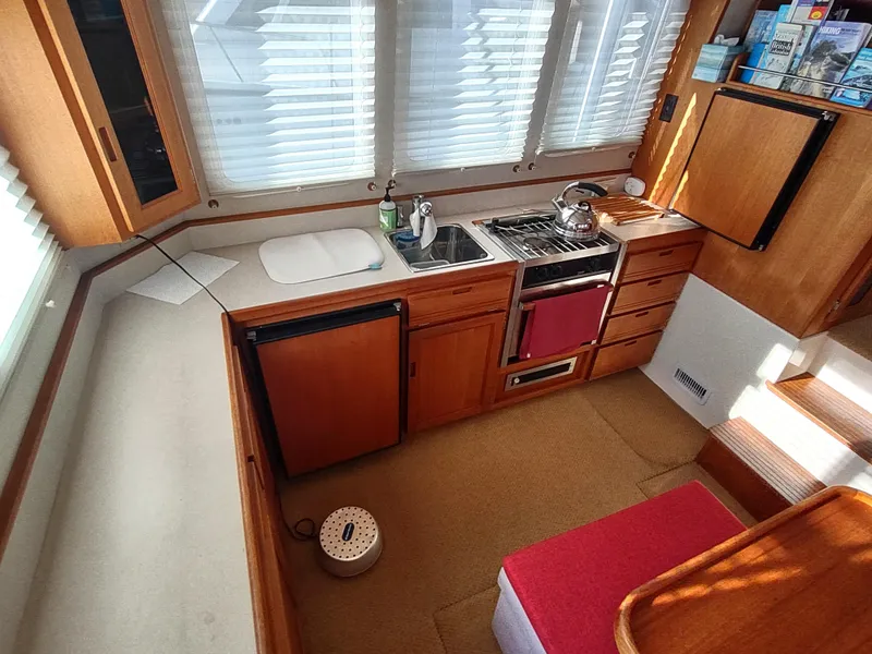 Slide: The Image of 2006 Nordic Tug 32 galley with stove, sink, and wooden cabinetry. - 16