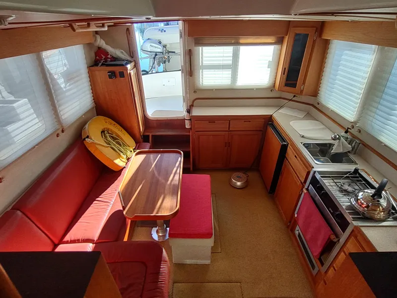Slide: The Image of Interior of 2006 Nordic Tug 32 with red seating, kitchen, and dining area. - 22